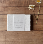 White textured box with text on a wooden surface with flowers