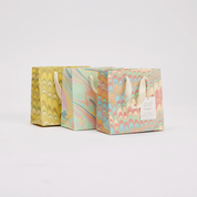 Three pastel marbled gift bags with handles on a light gray background