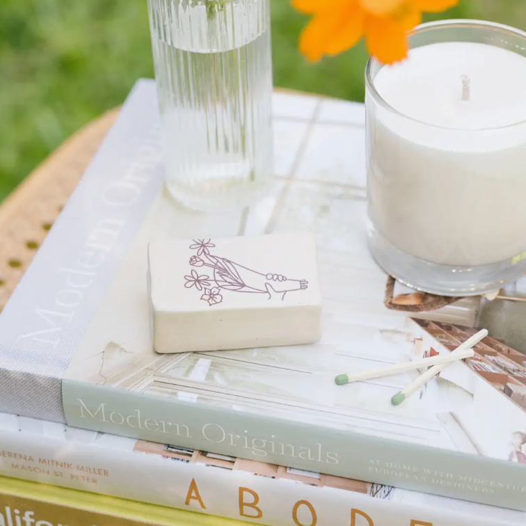 Stack of books with a candle, matches, and a decorative matchbox on top