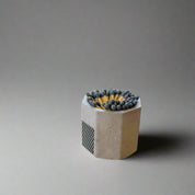 Concrete matchbox holder with matches on a wooden surface near a window.