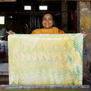 Woman holding a large piece of fabric with a textured pattern in an indoor setting.
