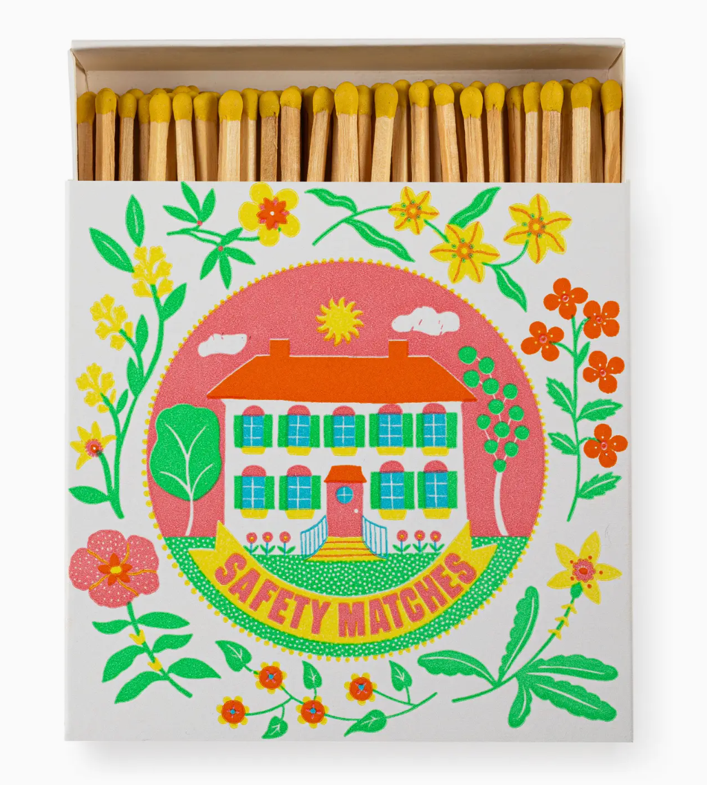 Matches with decorative packaging featuring a house and flowers on a white background