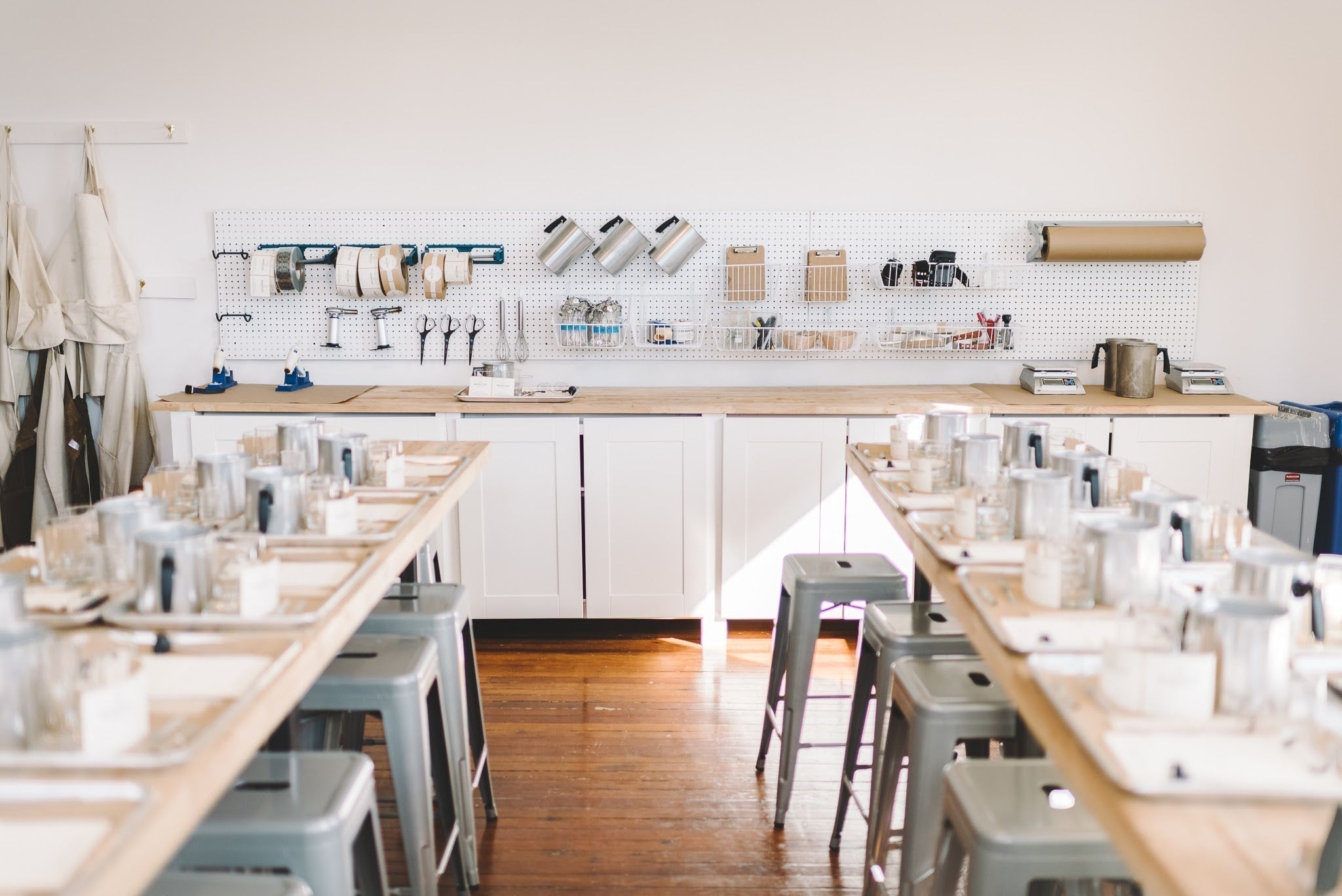 image of a workshop classroom for candle making gatherings. all of the products needed to make candles, including chairs, tables, wicks, wax pouring pitchers, and more