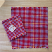 Red and lavender checkered fabric with frayed edges on a wooden surface