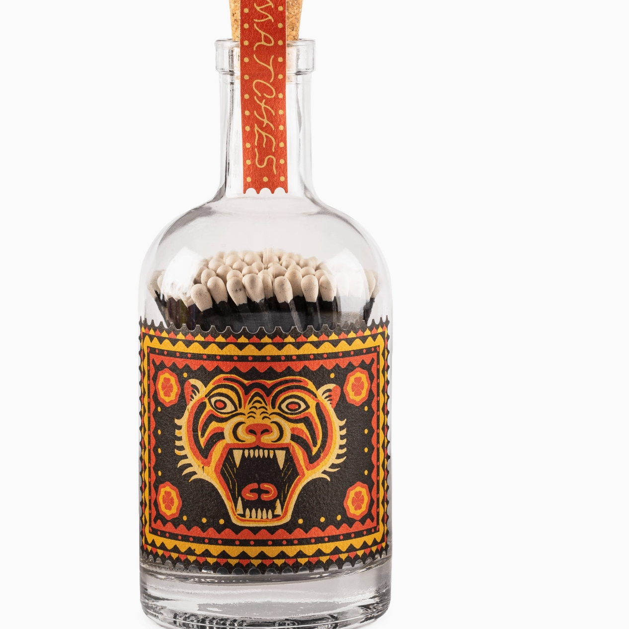Matches in a glass bottle with decorative tiger design on a white background