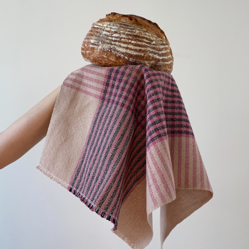 Textured fabric with a loaf of bread on a plain background