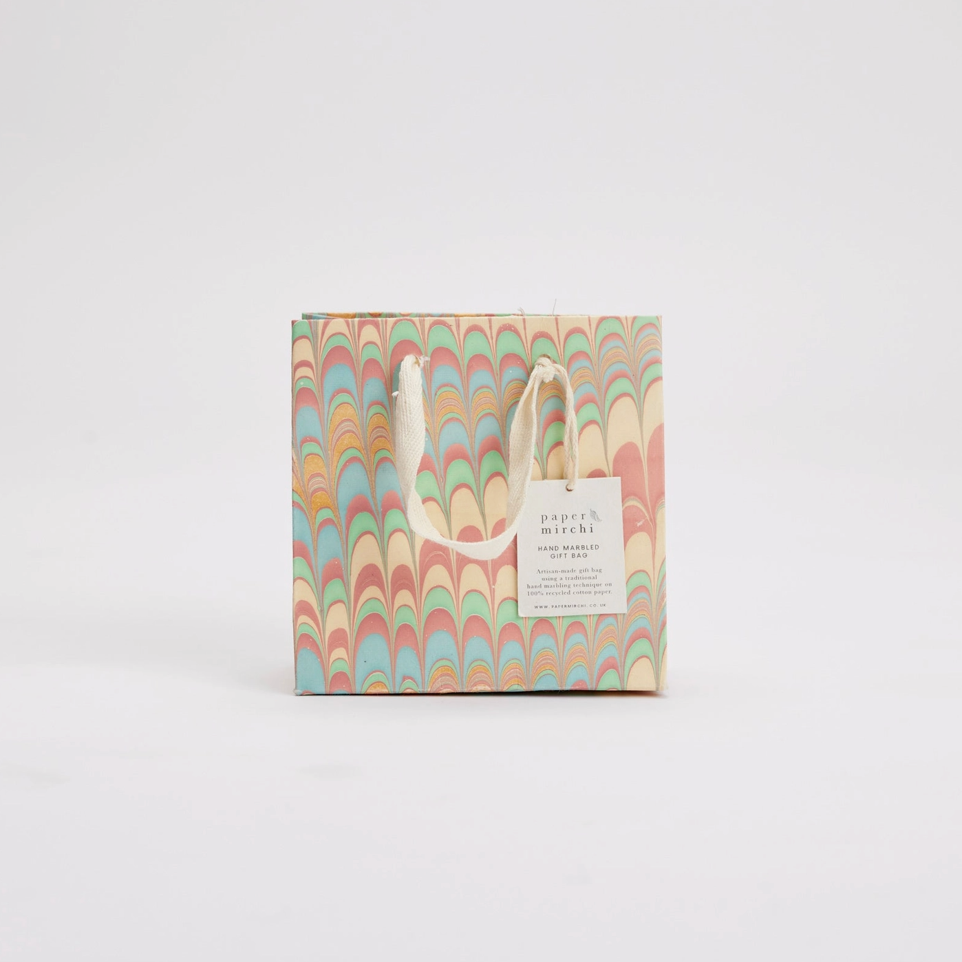 Colorful patterned gift bag with a white handle on a light gray background