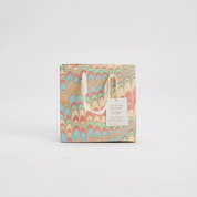 Colorful patterned gift bag with a white handle on a light gray background