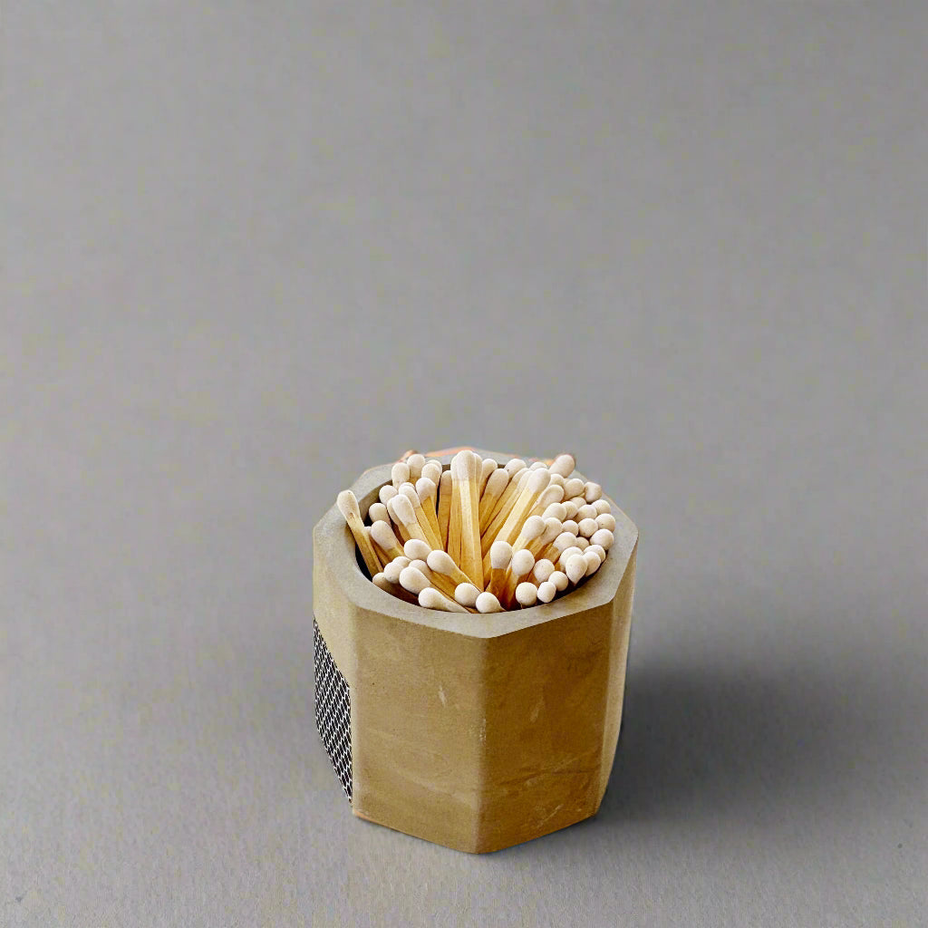 Hexagonal wooden matchbox with matches on a light wooden floor.