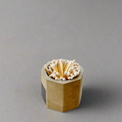 Hexagonal wooden matchbox with matches on a light wooden floor.