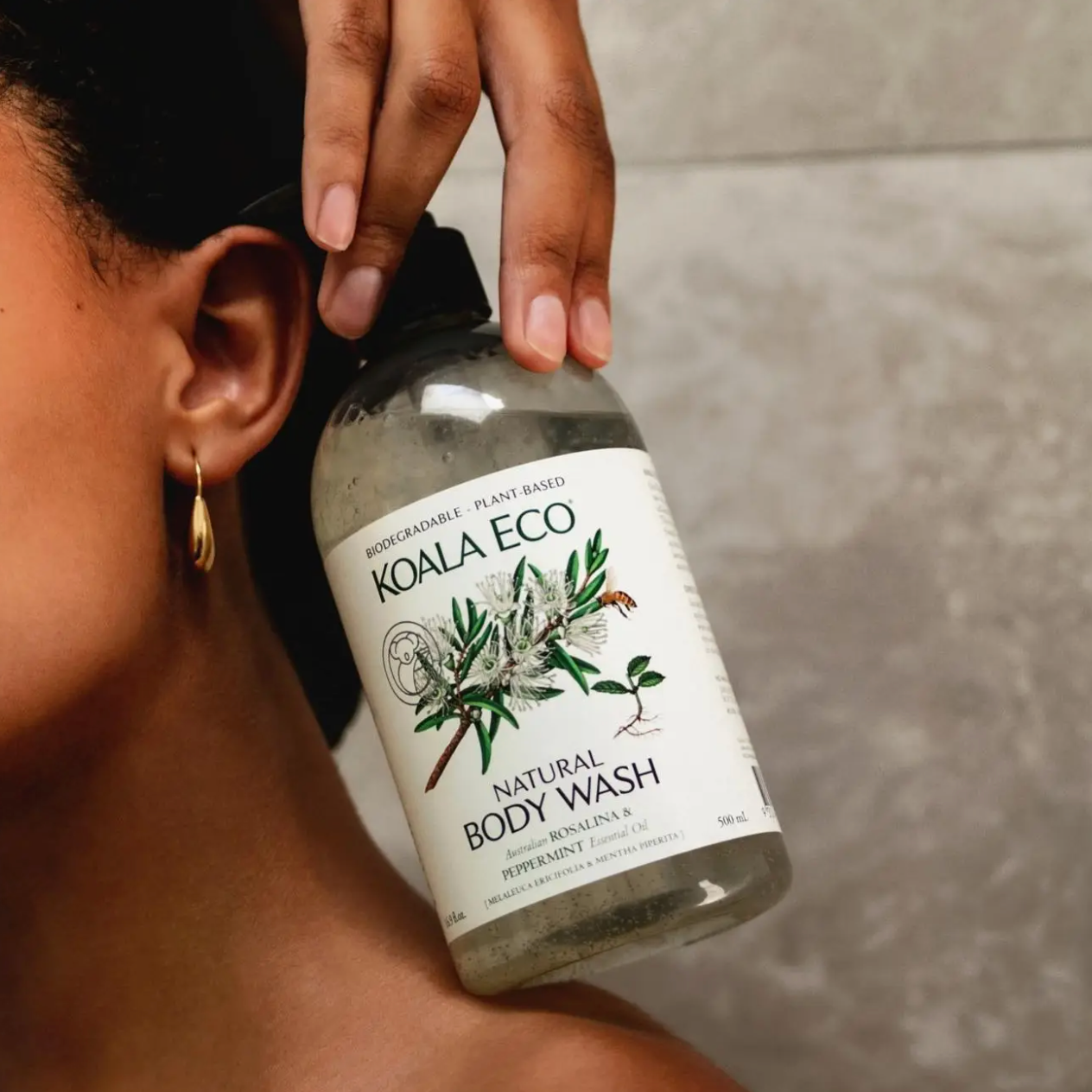 Person holding a bottle of Koala Eco natural body wash with a neutral background