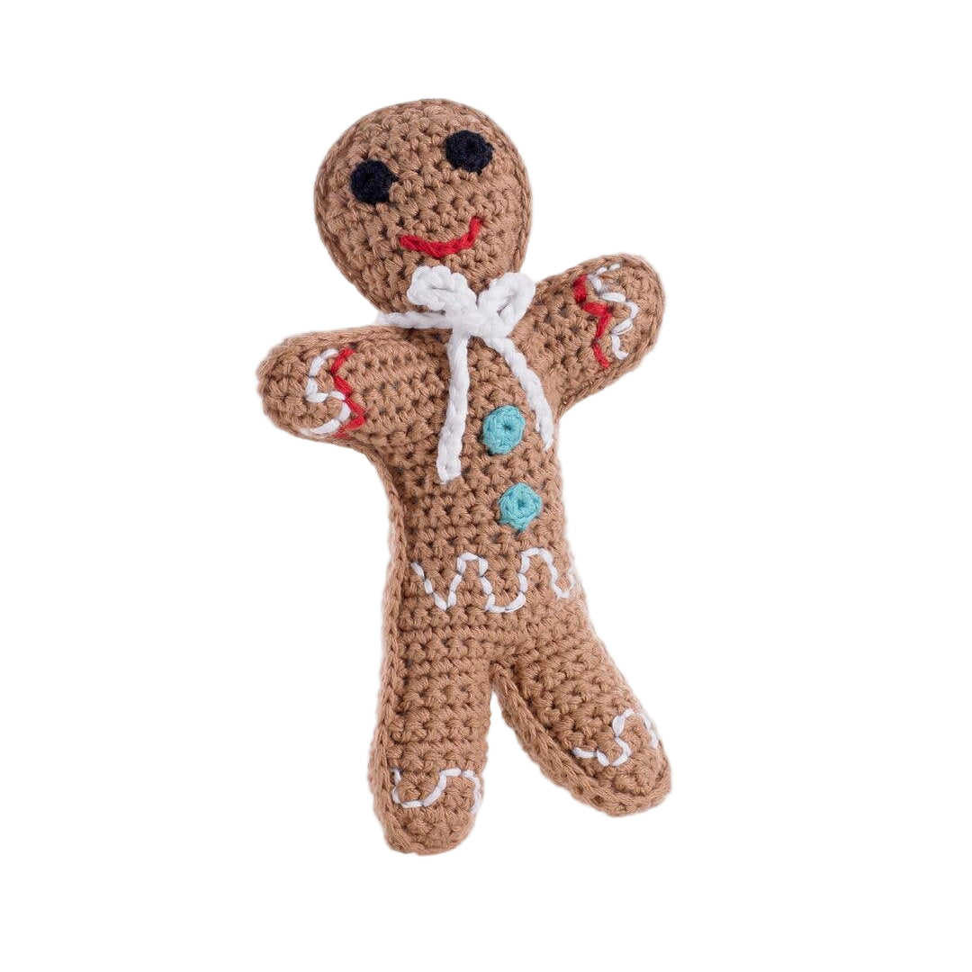A handmade knit toy resembling a gingerbread man with a happy facial expression, dressed in a colorful outfit with a white and red pattern, and a bow detail.