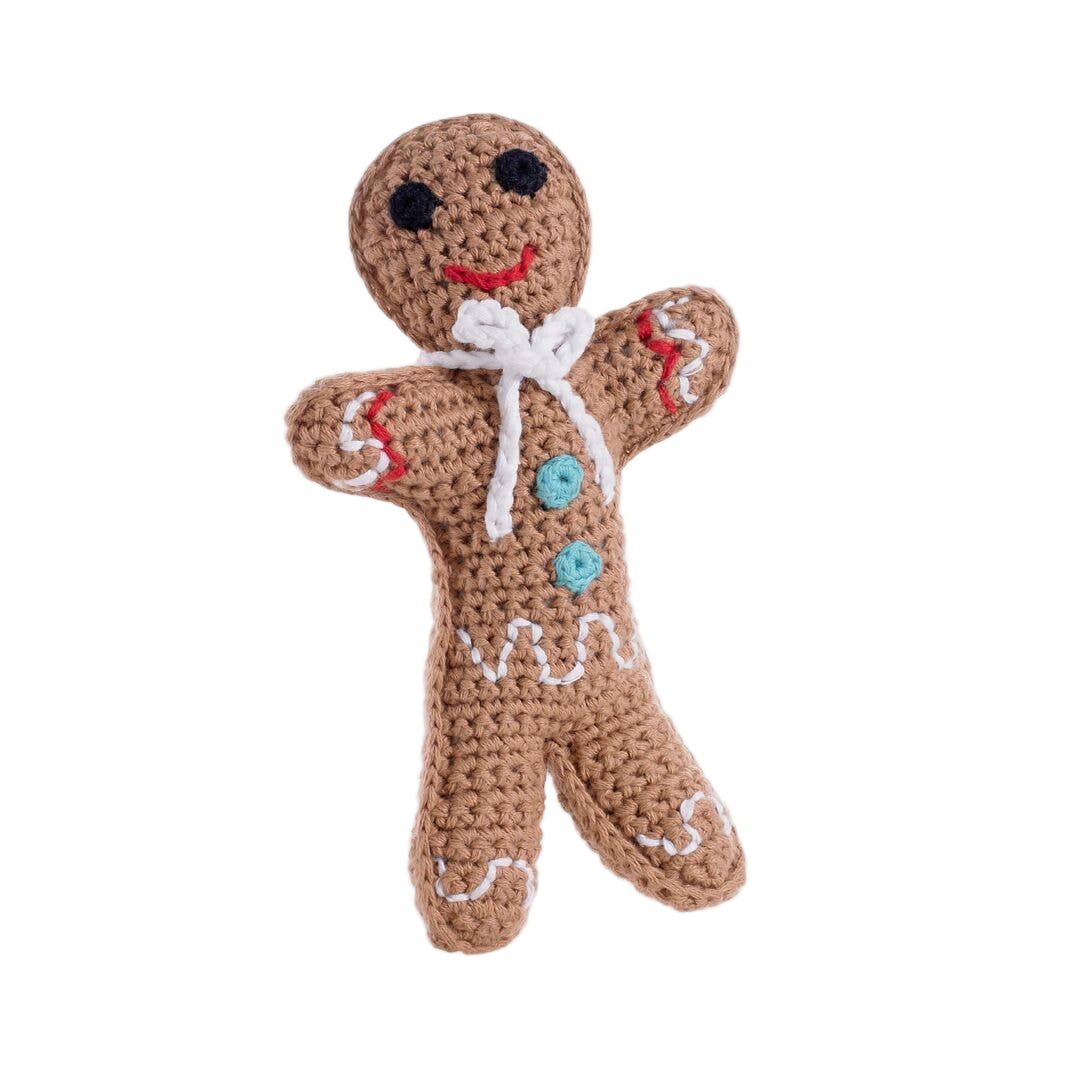 A handmade knit toy resembling a gingerbread man with a happy facial expression, dressed in a colorful outfit with a white and red pattern, and a bow detail.
